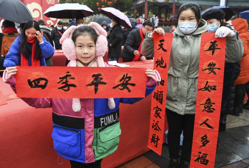 Une femme et sa fille montrent un couplet de la fête du Printemps qu'elles ont reçu lors d'une activité de composition de couplets dans l'arrondissement de Yongchuan
