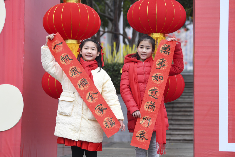 Deux filles montrent un couplet de la fête du Printemps lors d'une activité de composition de couplets dans l'arrondissement de Yongchuan