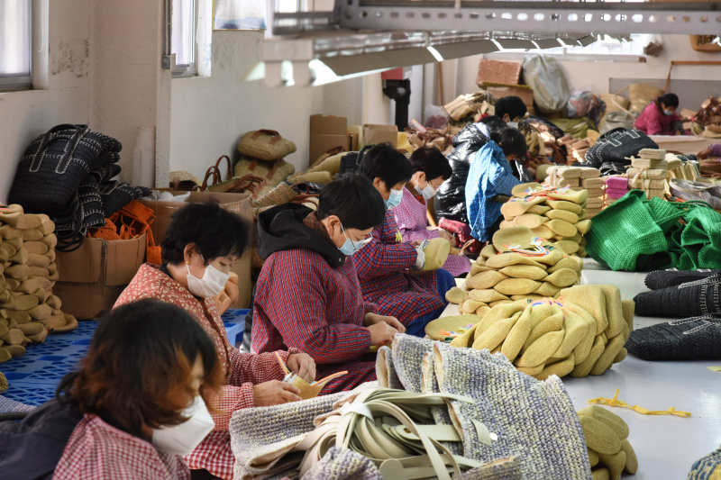 Des employés tissent de la paille dans une usine d'artisanat