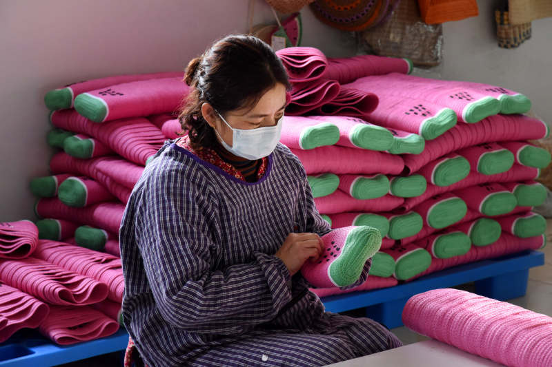 Une employée tisse de la paille dans une usine d'artisanat