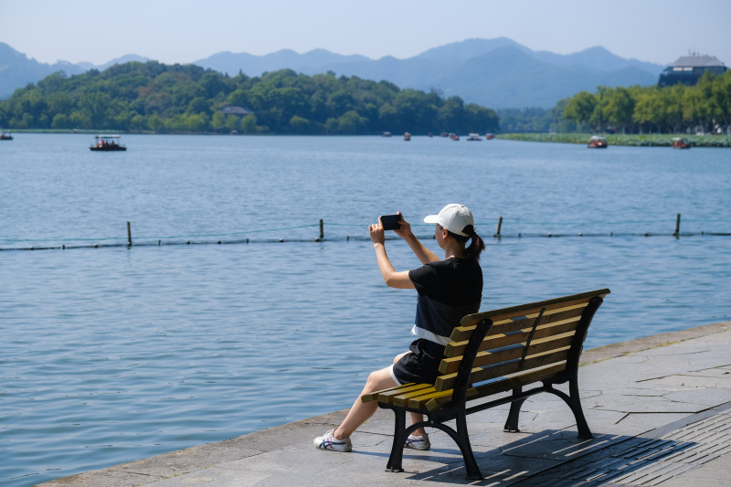 Une touriste prend des photos de la zone touristique du lac de l'Ouest pendant les congés de la fête nationale