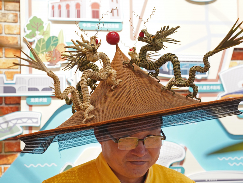 Un dépositaire du patrimoine culturel immatériel montre son chapeau illustrant le thème de l'Année du dragon lors d'une exposition sur les coutumes du Nouvel An lunaire chinois