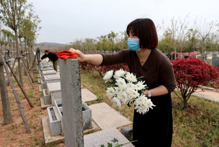 (miniature) Une bénévole rend hommage aux défunts au nom des personnes en deuil dans un cimetière du district de Quanjiao