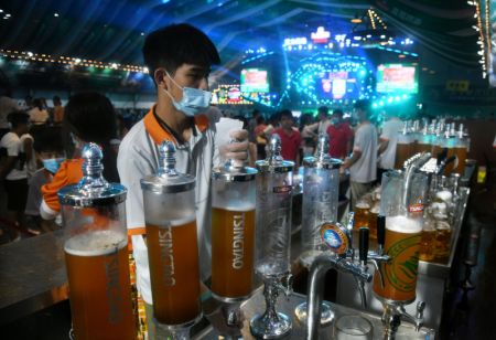 (miniature) Un membre du personnel sert de la bière à des visiteurs lors du 30e Festival international de la bière de Qingdao