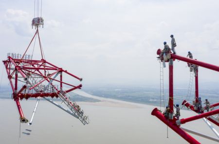 (miniature) Photo aérienne prise le 16 août 2022 montrant des techniciens travaillant sur le site de construction de la tour nord de transmission d'électricité du projet de transmission d'électricité à courant continu ultra-haute tension (UHV) de 800 kilovolts de Baihetan-Zhejiang sur le fleuve Yangtsé à Tongling
