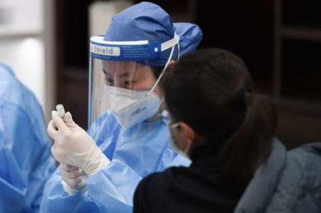 (miniature) Une professionnelle de la santé se prépare à administrer une dose de vaccin contre le COVID-19 à une employée à Wangfujing