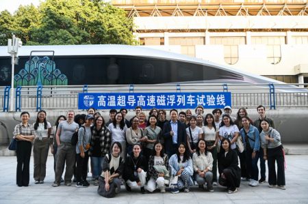 (miniature) Des étudiants américains participant à une tournée éducative en Chine posent pour une photo de groupe à côté d'un prototype de locomotive utilisant la technologie maglev supraconductrice à haute température à Chengdu
