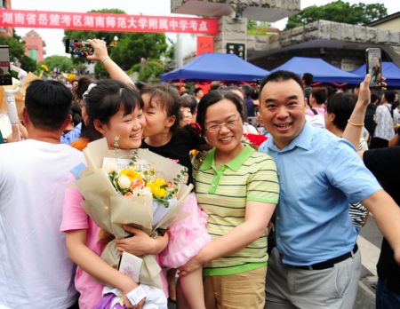 (miniature) Une candidate tenant un bouquet de fleurs prend une photo avec ses parents devant un site d'examen du concours national d'entrée à l'université à Changsha