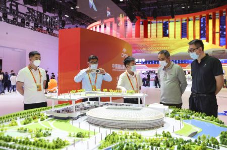 (miniature) Des gens devant une maquette du Stade des travailleurs lors de l'exposition sur les réalisations du commerce des services de la Chine