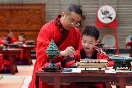 (miniature) Un enfant et son père participent à la cérémonie d'initiation à l'écriture First Writing Ceremony