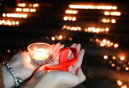 (miniature) Une personne tient une bougie et un ruban rouge lors d'un événement de sensibilisation sur le sida à l'Université Nanhua