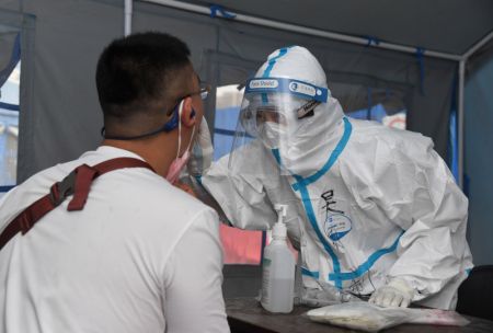 (miniature) Un professionnel de santé effectue un prélèvement de gorge sur un habitant dans un site de test d'acide nucléique