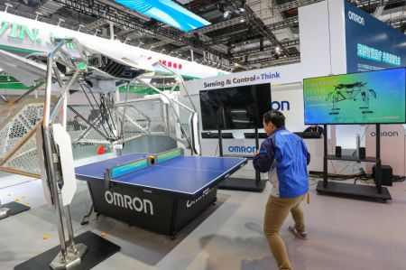 (miniature) Un employé teste un robot d'entraînement pour le tennis de table sur le stand d'Omron