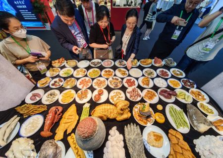 (miniature) Des personnes regardent des plats chinois traditionnels fabriqués avec la pierre de Shoushan lors de la quatrième Exposition internationale des produits de consommation de Chine à Haikou