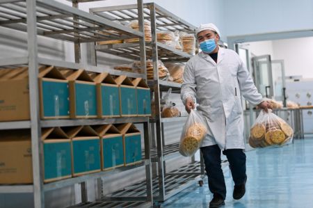 (miniature) Un ouvrier distribue des pains locaux plats (Nang) nouvellement préparés dans un atelier d'un parc industriel à Horgos