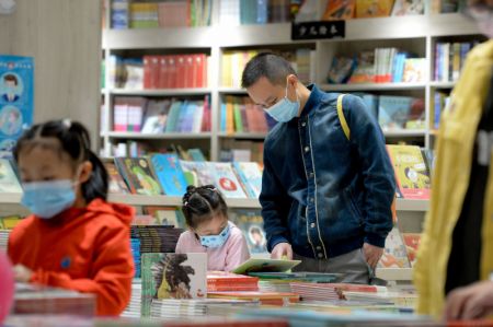 (miniature) Un père aide sa fille à sélectionner des livres dans une librairie à Urumqi