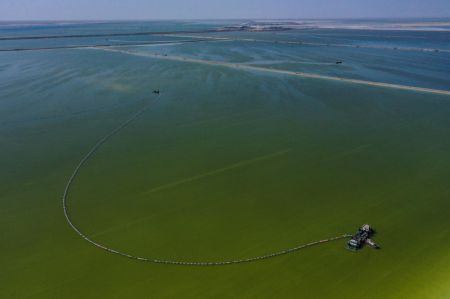(miniature) Photo aérienne prise le 1er avril 2022 montrant un bateau collectant du sel brut dans un lac salé de la province chinoise du Qinghai (nord-ouest)
