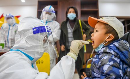 (miniature) Un professionnel de santé prélève un échantillon de gorge sur un enfant pour des tests d'acide nucléique dans un site temporaire de dépistage à Hohhot