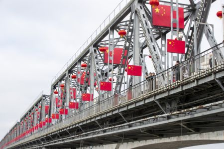 (miniature) Des touristes sur un pont où sont accrochés des drapeaux nationaux à Harbin