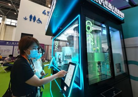 (miniature) Des visiteuses passent une commande sur une machine à café robotisée à la deuxième Exposition internationale des produits de consommation de Chine