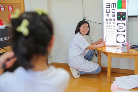 (miniature) Une ophtalmologiste contrôle la vue d'une petite fille dans une école maternelle du district de Deqing à Huzhou