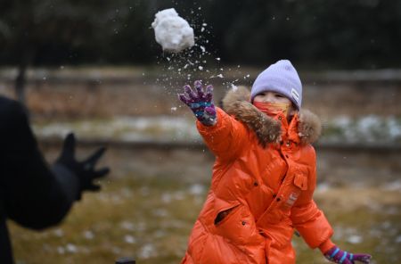 (miniature) Un enfant s'amuse avec la neige dans la rue