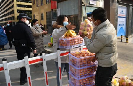 (miniature) Un employé d'une épicerie livre des fruits à une habitante dans un quartier de Xi'an