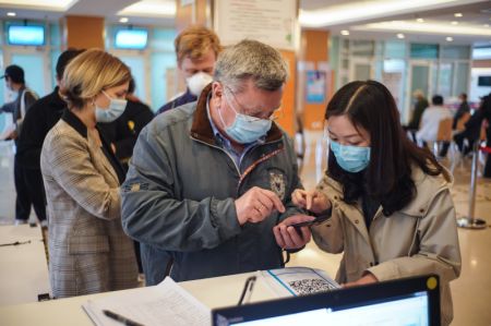 (miniature) Une interprète bénévole aide un ressortissant étranger à s'inscrire pour la vaccination dans un site de vaccination à Beijing
