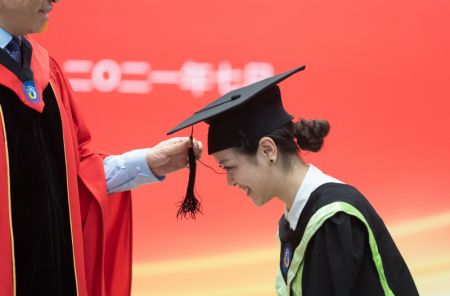 (miniature) La houppe de la toque universitaire d'une diplômée tournée par un professeur lors d'une cérémonie de remise des diplômes à l'Université des langues étrangères de Beijing (BFSU)