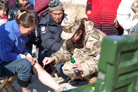 (miniature) Un membre de la Force de la Police armée populaire fournit des services médicaux à des personnes touchées par le séisme dans le bourg de Liuji du district de Jishishan