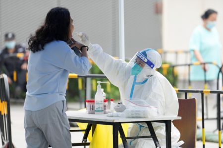 (miniature) Un agent médical prélève un échantillon de gorge sur une habitante pour un test d'acide nucléique à Balizhuang dans l'arrondissement de Chaoyang
