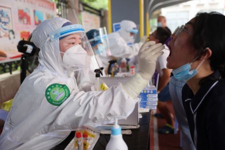 (miniature) Une professionnelle de la santé prélève un échantillon de gorge sur une habitante dans un site de dépistage à Xiamen