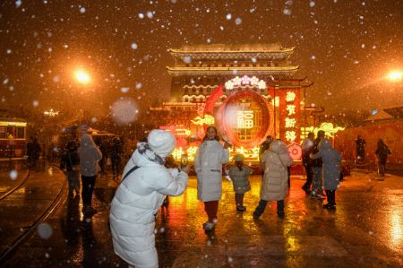 (miniature) Des touristes posent pour des photos dans la rue Qianmen sous la neige