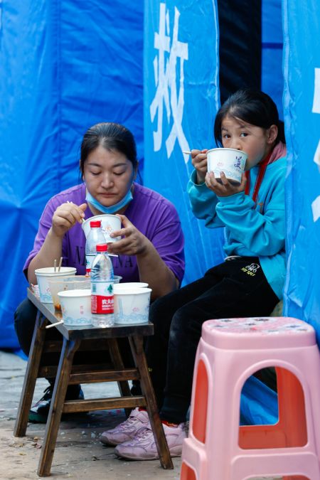 (miniature) Des personnes prennent un repas dans un abri d'urgence après le séisme dans le bourg de Moxi du district de Luding