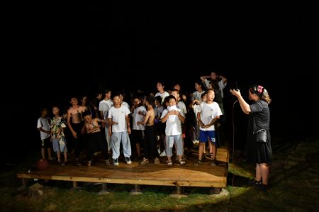 (miniature) Zhou Yan (à droite) présente au public les enfants participant à un spectacle dans le district de Ningyuan de la province chinoise du Hunan (centre)