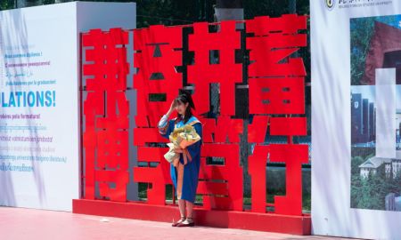 (miniature) Une diplômée pose pour une photo lors de la cérémonie de remise des diplômes à l'Université des langues étrangères de Beijing (BFSU)