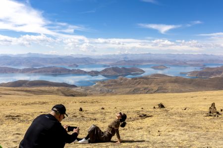 (miniature) Un touriste pose pour une photo avec le lac Yamzbog Yumco en arrière-plan