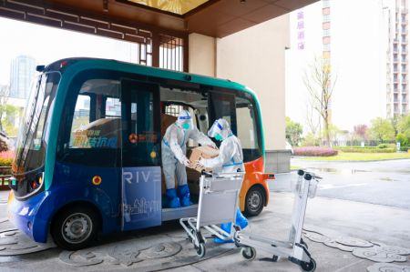 (miniature) Des employés déchargent des fournitures d'un véhicule autonome de livraison dans un hôtel de quarantaine pour la COVID-19 à Hefei