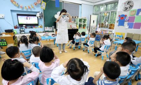 (miniature) Une professionnelle de la santé montre à des enfants d'une école maternelle de Suzhou comment faire des exercices oculaires