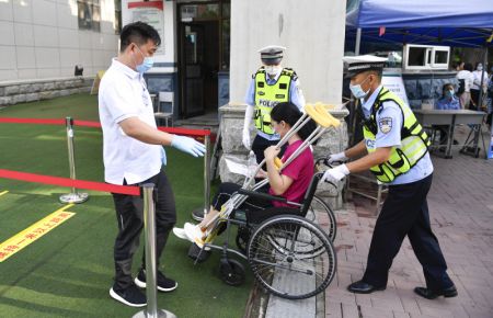 (miniature) Un policier aide une candidate handicapée à entrer dans le site d'examen dans un lycée à Changchun