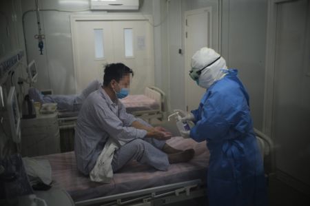 (miniature) Une infirmière désinfecte les mains d'un patient du COVID-19 dans une salle d'isolement de l'hôpital Ditan