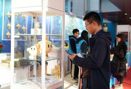 (miniature) Un visiteur regarde des produits de la mascotte de l'Exposition de la chaîne d'approvisionnement internationale de Chine (China International Supply Chain Expo