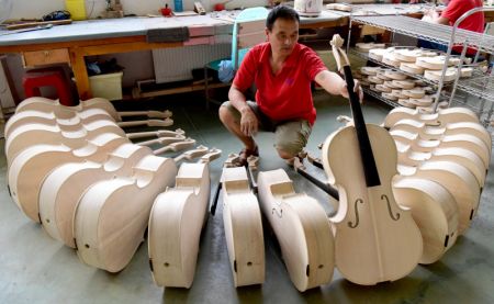 (miniature) Un ouvrier vérifie un violoncelle dans un atelier dans un parc industriel de production d'instruments de musique à Queshan