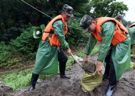 (miniature) Des membres de la police armée renforcent la section de Sanlongwei de la digue dans le bourg de Baimao