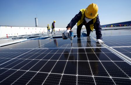 (miniature) Un travailleur installe des panneaux photovoltaïques sur le toit d'une usine