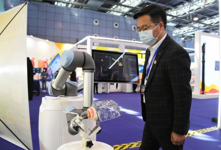 (miniature) Un visiteur regarde un robot destiné à la chirurgie buccale lors d'une exposition pour marquer la Semaine nationale de l'innovation et de l'entrepreneuriat de masse 2021