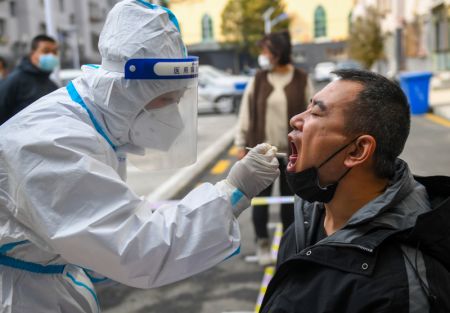 (miniature) Un professionnel de santé prélève un échantillon de gorge sur un habitant pour des tests d'acide nucléique dans un site temporaire de dépistage à Hohhot