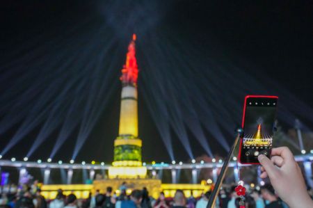 (miniature) Un visiteur prend des photos d'un spectacle de lumière organisé sur une place à Harbin