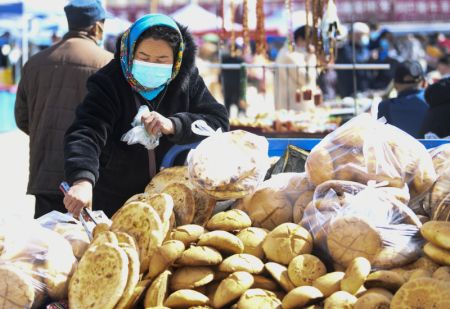 (miniature) Une vendeuse prépare des produits alimentaires pour la vente dans un bazar de Hami