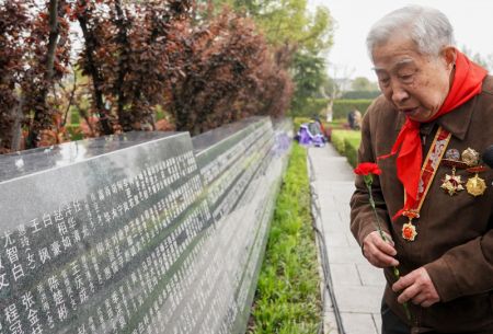 (miniature) Le vétéran Liu Tiantong dépose une fleur devant un mur commémoratif à Shanghai